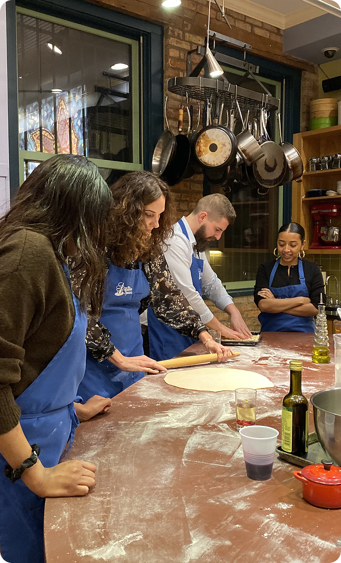 Members of the GRANITE team in aprons rolling pizza dough at a cookery class